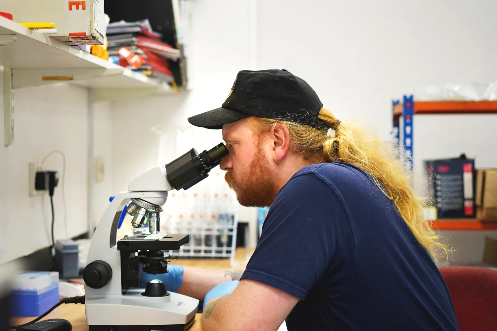 An Abbeydale brewer examining a beer sample under a microscope in the brewery's lab