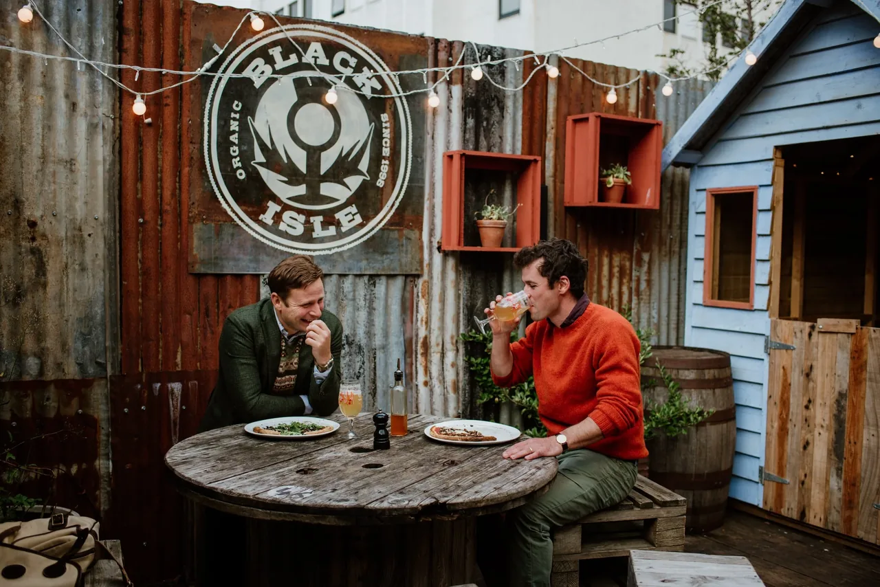 Drinkers enjoying Black Isle beer at a table under the brewery's organic logo